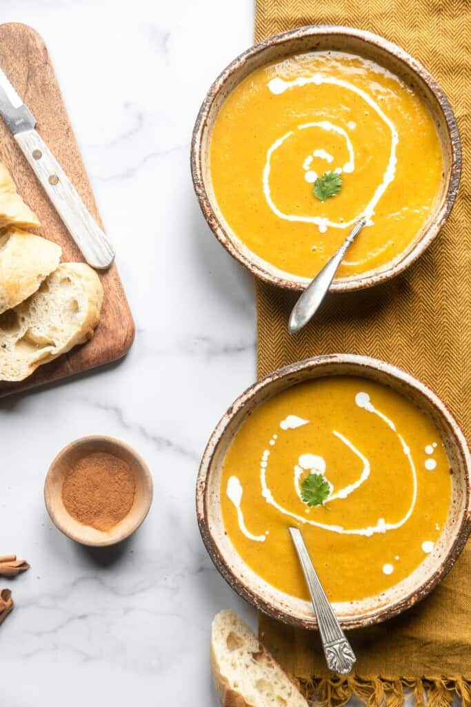 two bowls of Instant Pot Butternut Squash Soup on a table with spoons