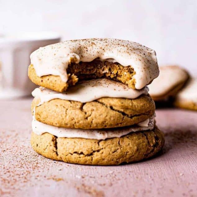 stack of 3 pumpkin sugar cookies with bourbon cinnamon frosting on a table