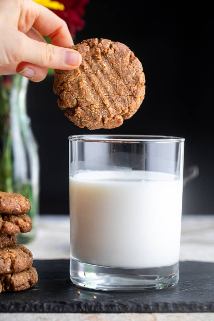 one almond flour peanut butter cookies being dipped into milk