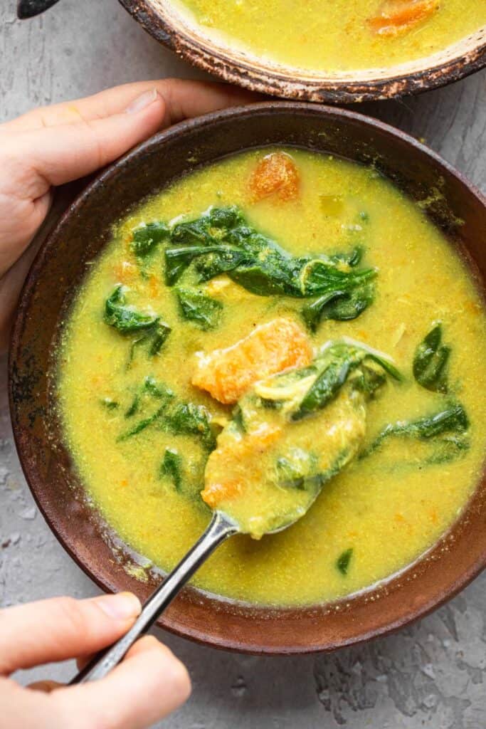 Whole30 Instant Pot Turmeric Tahini Chicken Soup in a bowl being eaten with a spoon