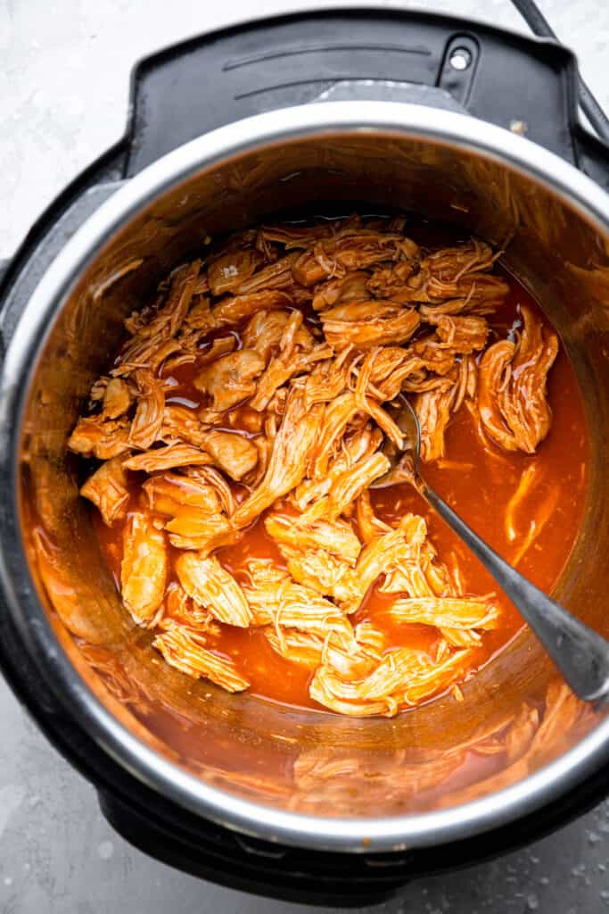 Instant Pot Buffalo Chicken being stirred together in pot