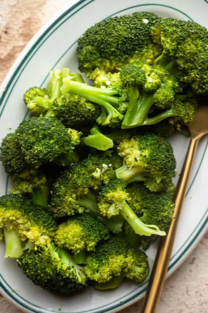 Instant Pot Steamed Broccoli on a dinner plate with a fork on the side