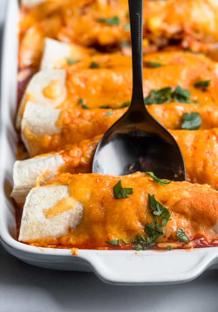 a dish of Instant Pot Chicken Enchilada with a spoon inserted