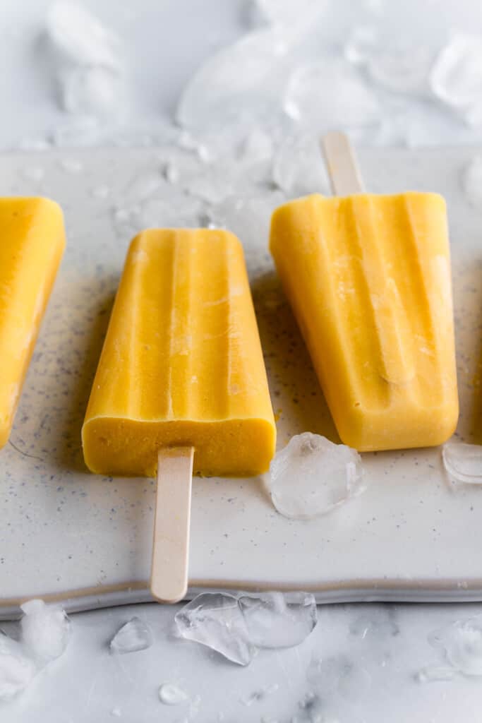 two Mango Popsicles on a board