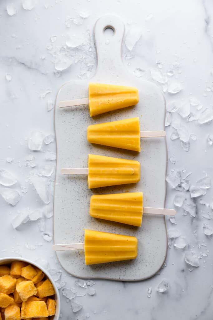 five Mango Popsicles on a serving board