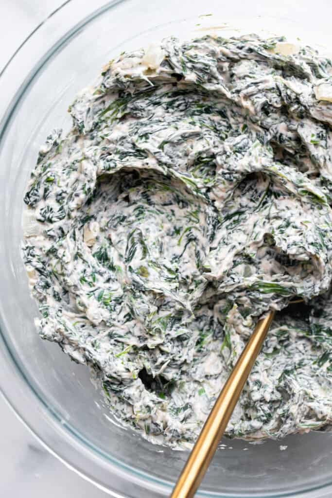 a bowl of Vegan Spinach Dip being stirred