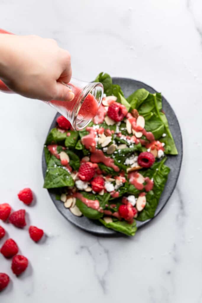 Raspberry Vinaigrette being poured on a salad