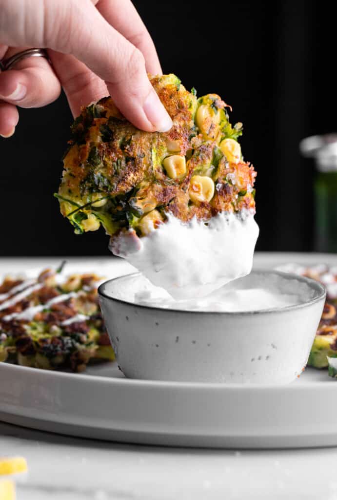 a Zucchini Corn Fritter being dipped into sour cream