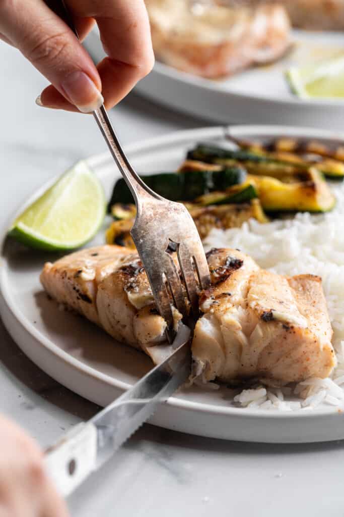 a serving of Grilled Grouper being cut up on a plate