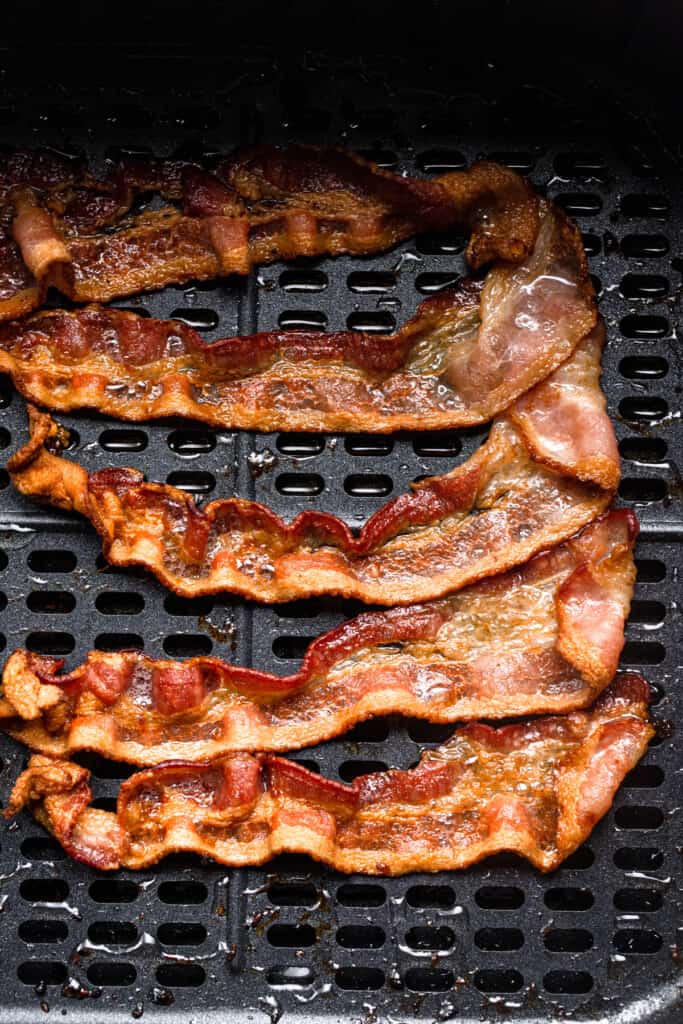 slices of air fryer bacon on an air fryer tray