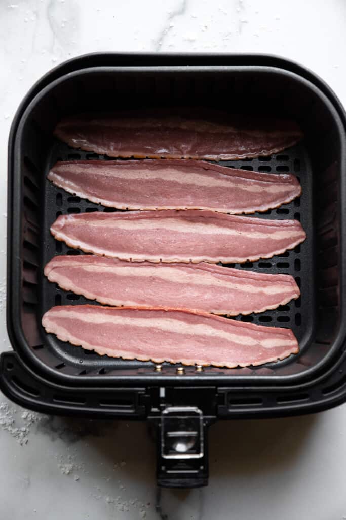 raw Air Fryer Turkey Bacon arranged in the air fryer
