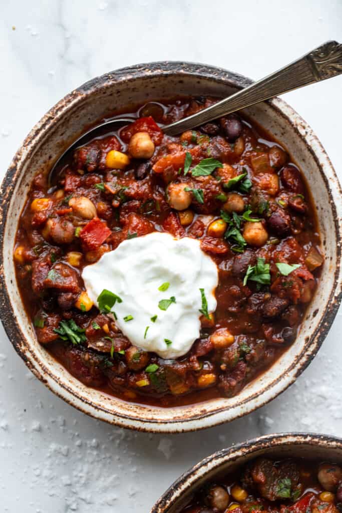 a bowl of Crockpot Vegetarian Chili with a spoon and sour cream