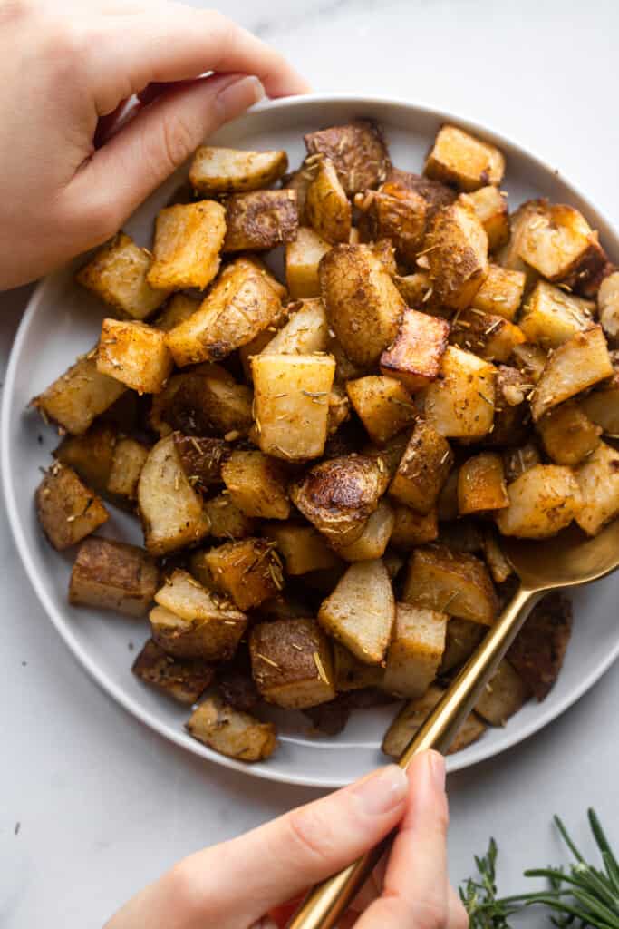 a bowl full of Roasted Russet Potatoes with a spoon