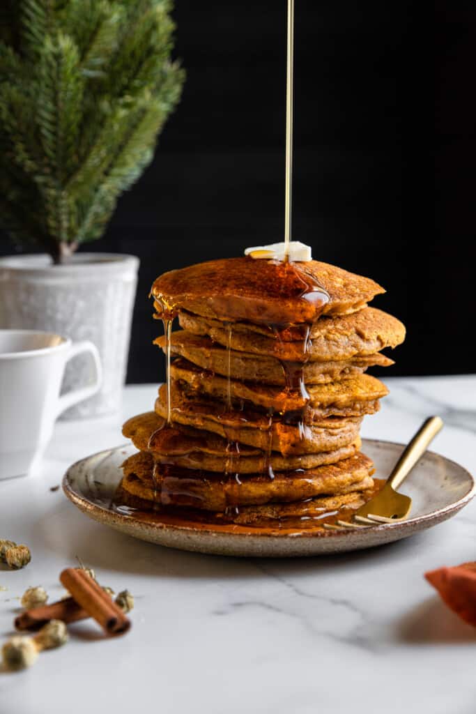 syrup being poured over a stack of Vegan Pumpkin Pancakes