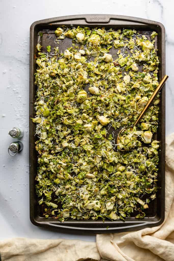 Shaved Brussels Sprouts Recipe spread on a baking sheet with a spoon
