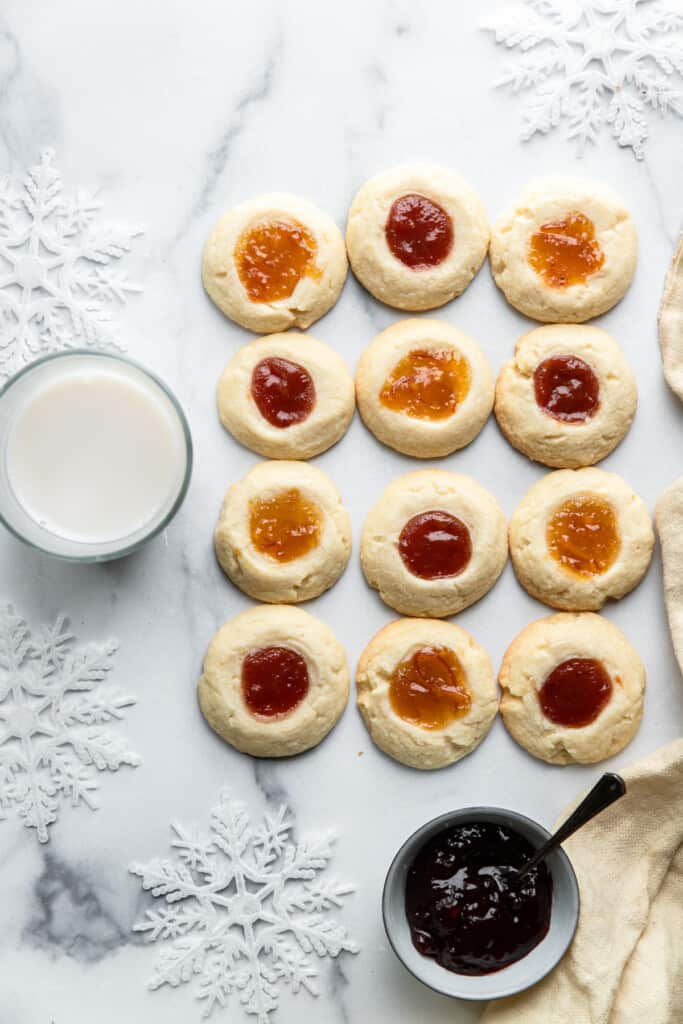 a bunch of Shortbread Cookies with Jam on a table with milk and jam on the side
