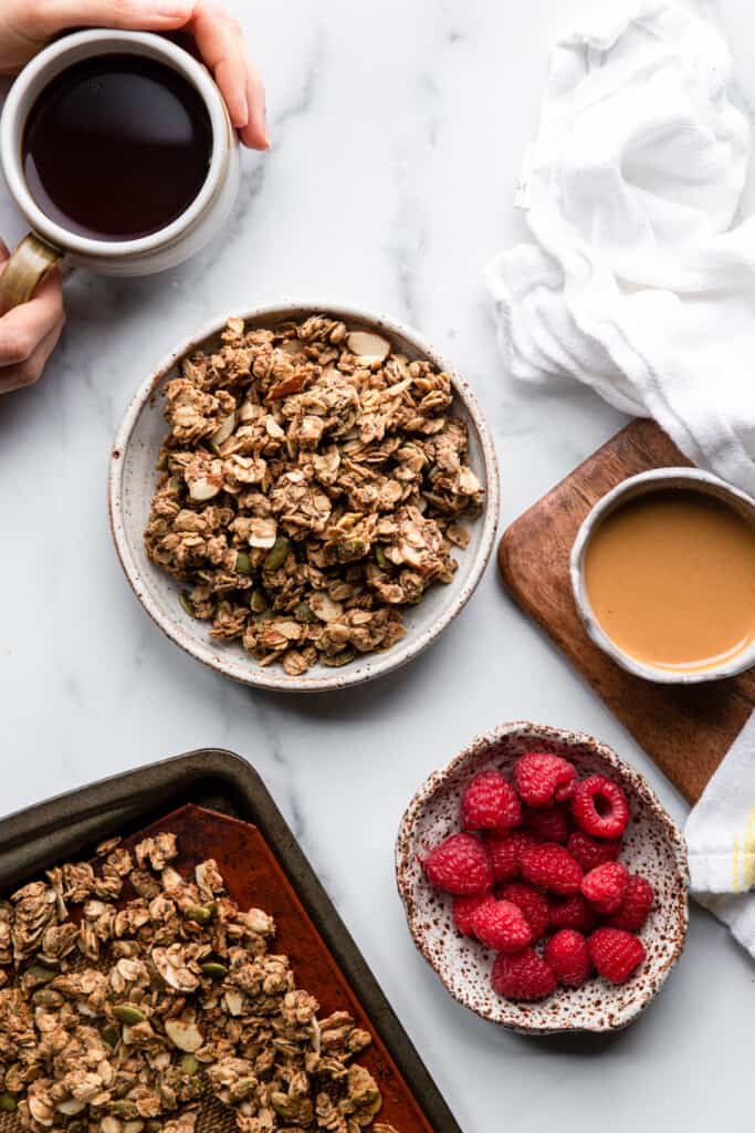 a bowl of Protein Granola on a table with toppings on the side