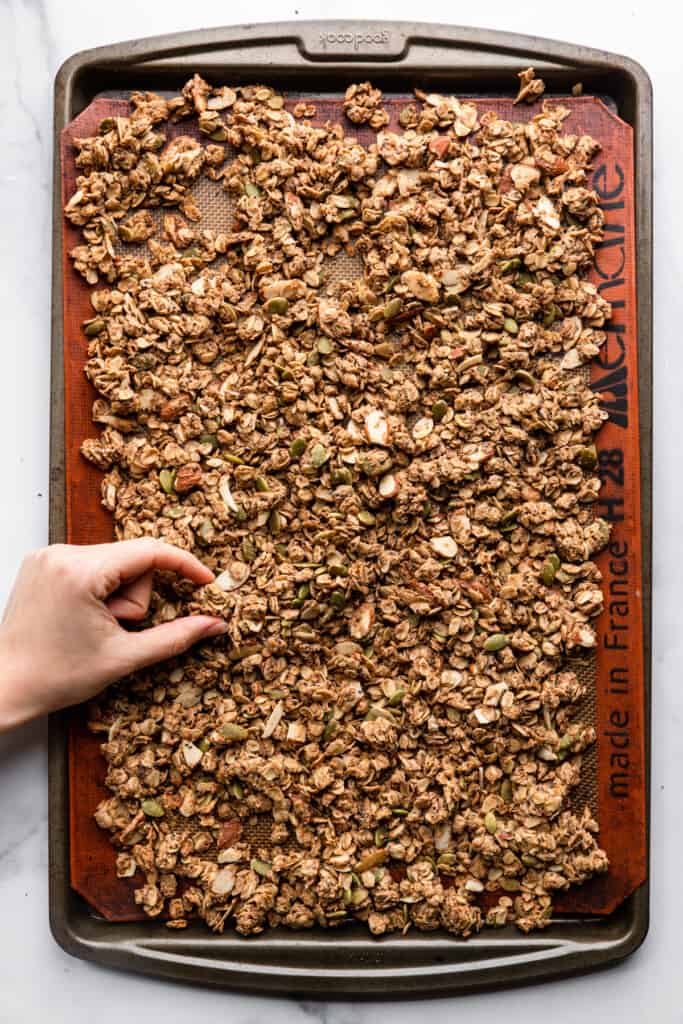 Protein Granola being picked up off a baking sheet