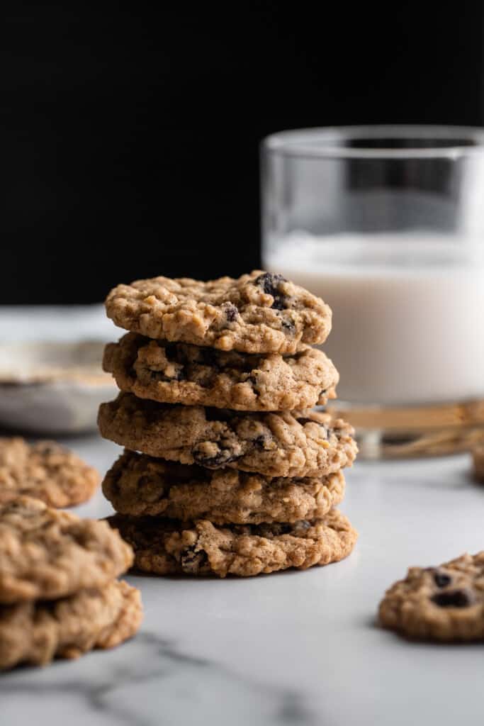 a stack of Vegan Oatmeal Raisin Cookies with a glass of milk