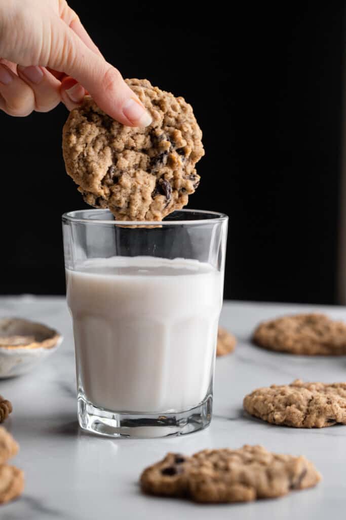 a Vegan Oatmeal Raisin Cookie being dipped into milk