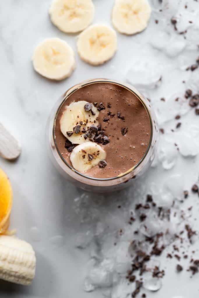 a glass of Chocolate Peanut Butter Banana Smoothie with bananas on top