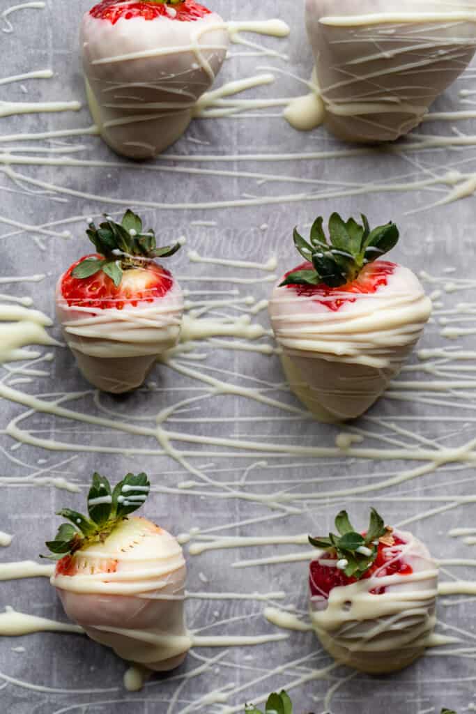 White Chocolate Covered Strawberries on a baking sheet drizzled with chocolate