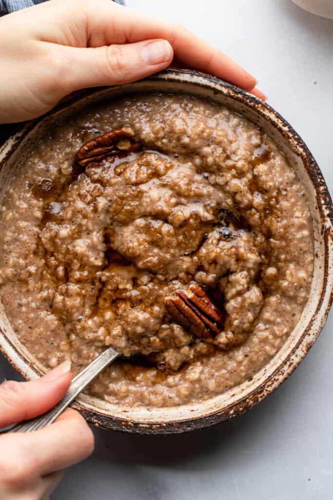 holding a bowl of Maple Brown Sugar Oatmeal with a spoon