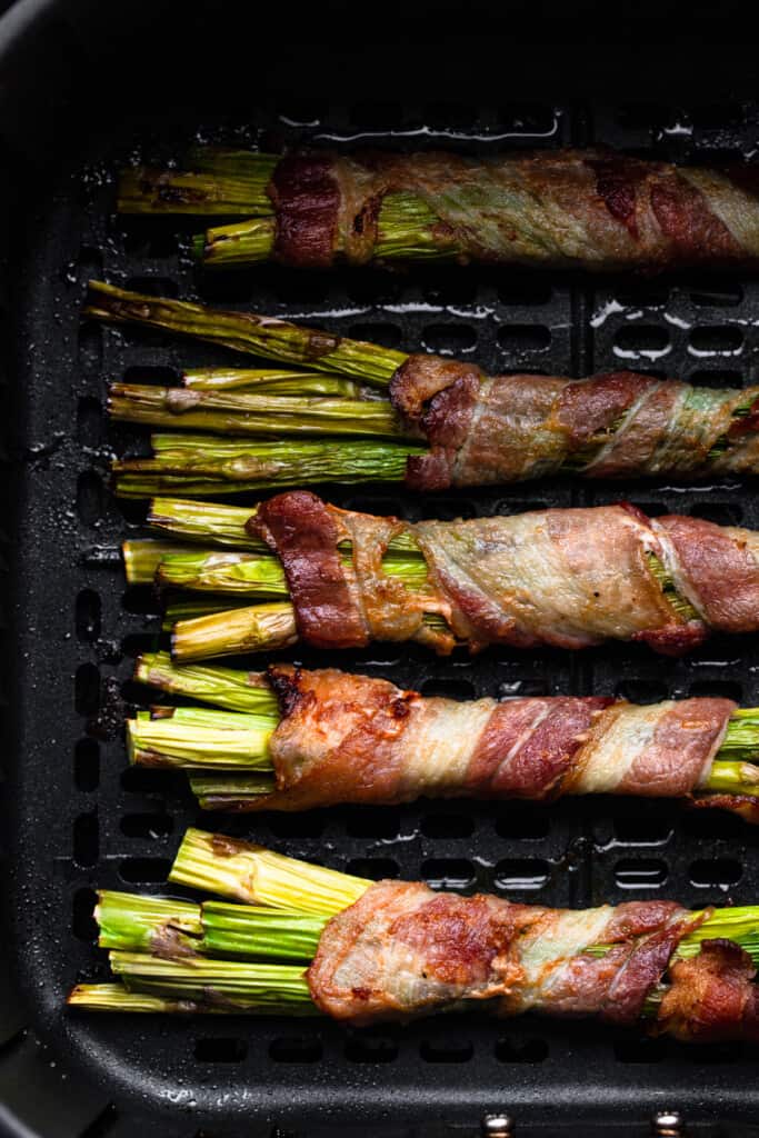 Air Fryer Bacon Wrapped Asparagus layered in an air fryer
